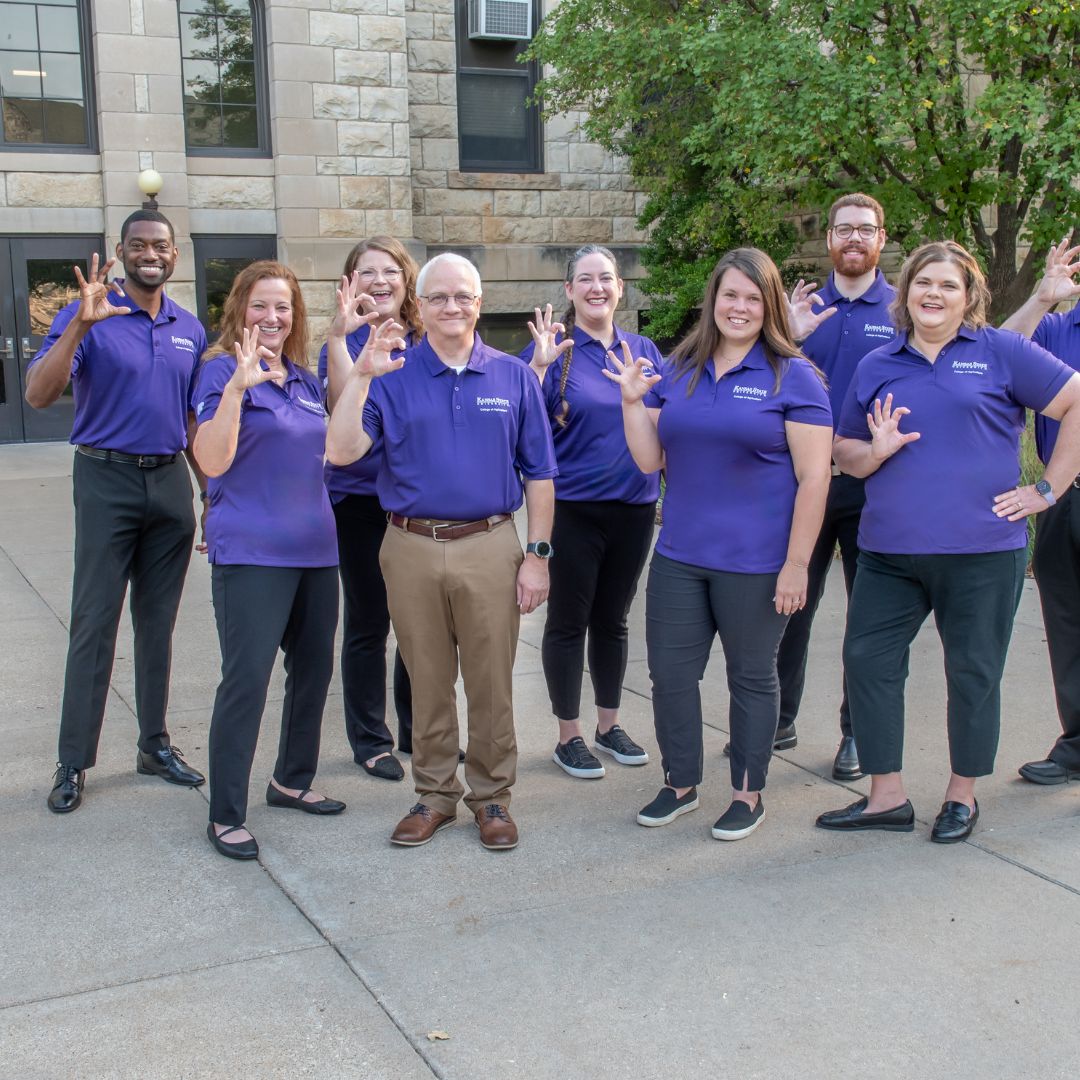 Group of advisors posing with purple polos and the Wildcat handsignal