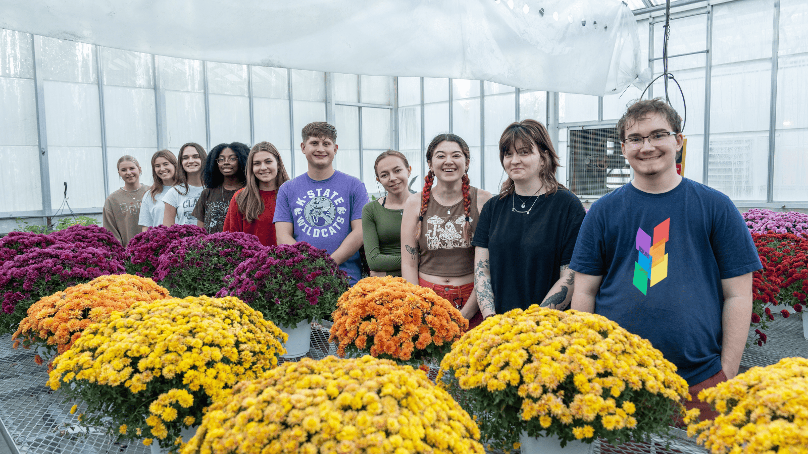 Students posing with mums in the greenhouse
