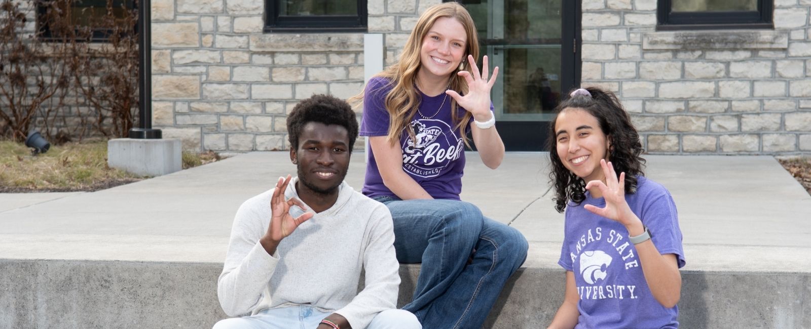 A group of three students doing the Wildcat hand sign